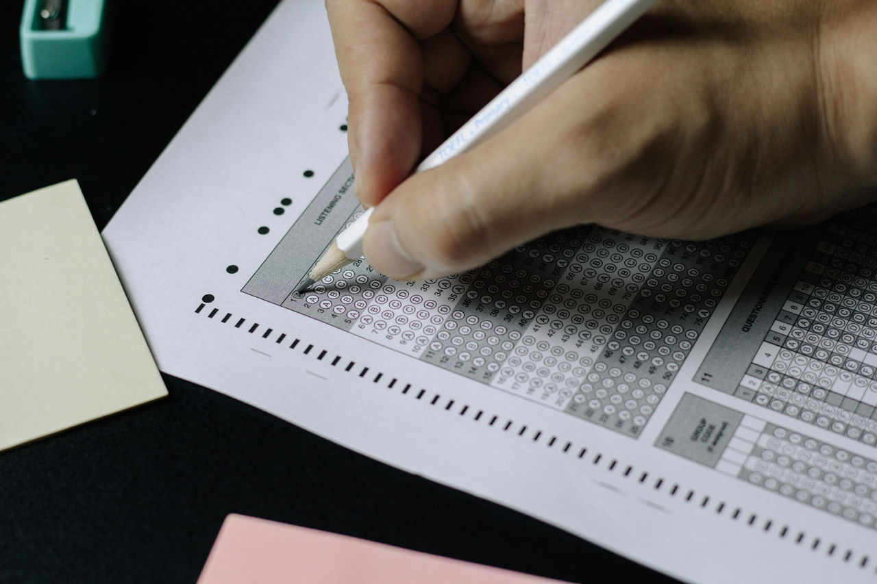 hand holding white pencil filling out survey