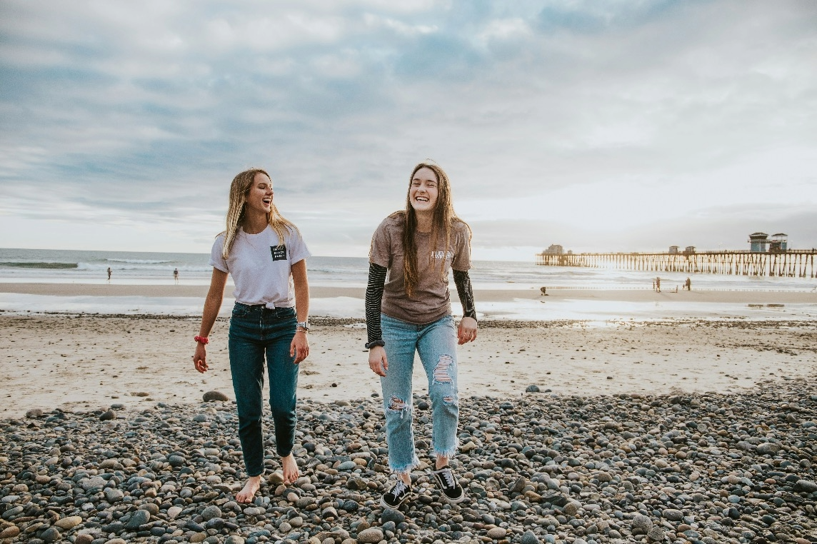 Friends walking on rocky beach smiling